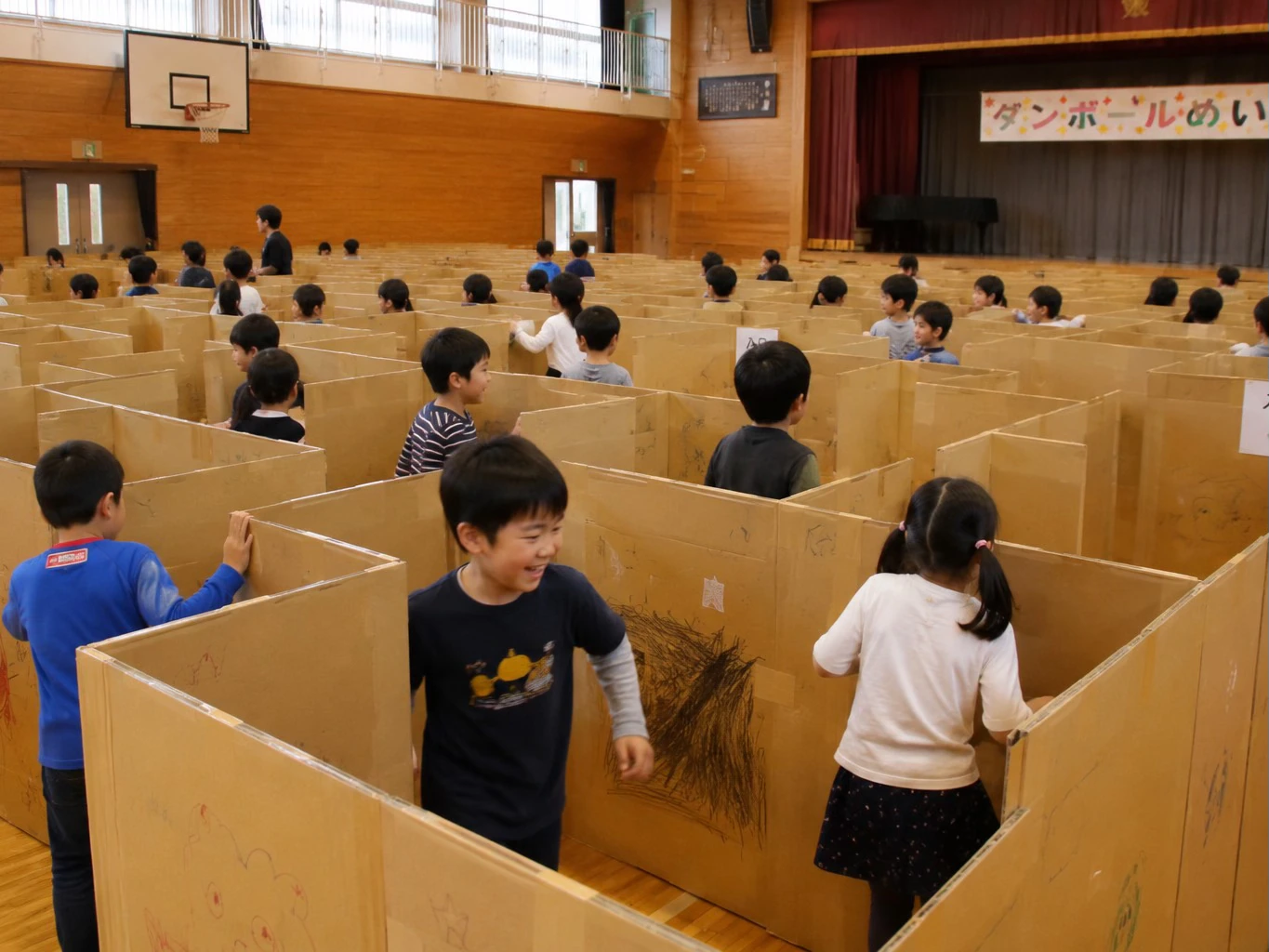 体育館の段ボール迷路で遊ぶ子どもたち